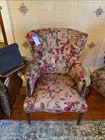 Front view of floral upholstered arm chair with matching fabric cover and wood legs.