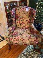 Front view of wingback chair showing floral upholstery and wooden legs