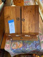 Top view of wooden letter box with two hinged doors closed showing tape residue and wood surface.