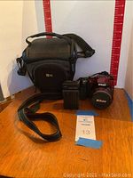 Front and side view of Nikon Coolpix P500 with camera bag, charger and battery visible