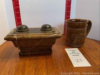 Front view of vintage marble inkwell and stoneware mug on wooden surface with measuring scale in background