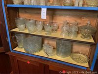 Glass cabinet shelf displaying the Wexford glassware collection including various plates, bowls, and serving pieces.