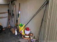 Wide shot of storage shed corner showing shovels, rakes, shepherds hooks, pots, potting soil bags and gardening containers.