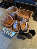 Overall assortment of baskets including wicker, metal containers, and the wooden floral planter showing condition and quantity.