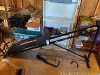 Total Gym fitness machine with inclined sliding bench, frame, and attachments shown from side angle in garage setting.