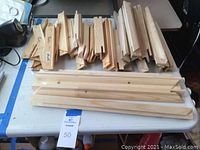 Image showing multiple wood stretcher bars arranged on a table. Bars are smooth natural wood, with finger joint ends for canvas assembly.