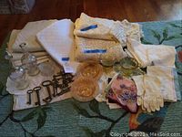 All vintage linens, gloves, keys, glass bowls, and tablecloths displayed together on floor
