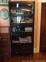 Front view of the full five-shelf bookcase with glass doors closed, contents inside