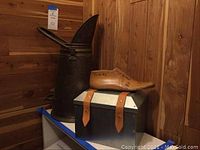 Shows the three items together: tall metal container, IKEA box, wooden shoe mold on top of box