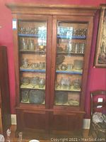 Full view of the vintage wooden hutch with glass front doors displaying shelves inside with some glassware (not included in sale).