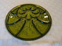 Round Forrest green glass deviled egg tray showing the segmented design with six egg-shaped cups and surrounding leaf-shaped sections embossed with leaf veins.