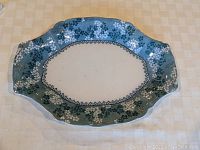 Full view of the oval-shaped platter with blue floral pattern on the rim and cream center.