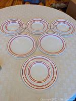 Six 10 1/2 inch dinner plates and four smaller 6 3/4 inch salad/luncheon plates with a red concentric ring pattern on white ceramic.