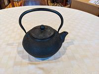 Large Japanese cast iron hobnail teapot with bail handle on a table; shows top-down angle highlighting lid and handle.