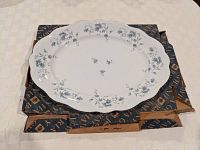 Top view of the Blue Garland porcelain platter with floral decoration laid on original box.