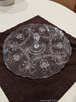 Full view of 14 inch clear glass center handled server plate with etched orchid floral designs on the surface, scalloped edge visible.
