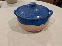 Side view of pastel glazed covered casserole bowl with lid on table, showing color transitions and side handles.