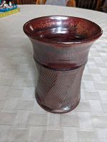 Front full view showing flared rim, rust brown glaze and cylindrical shape.