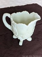 Creamer showing side and handle details, relief pattern, and scalloped rim.