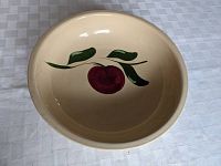 Top view showing interior design of red apple with green leaves on beige ceramic bowl.