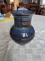 Front view of the hand-thrown pottery vase showing blue and bronze glaze, round body with narrower neck and flared top rim.