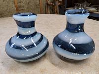 Pair of blue, white and grey swirled blown glass vases, side view showing shape and colors.