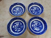 Four Homer Laughlin Blue Willow fruit bowls arranged in a cluster, showing their shape and decoration.