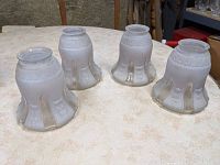 Four frosted camphor glass lamp shades arranged on a table, showing their shape and condition.