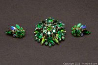 Front view of green rhinestone brooch and matching clip-on earrings showing vibrant stones and design