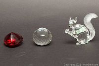 Photo showing red faceted paperweight, clear faceted sphere paperweight, and clear Swarovski crystal squirrel figurine from front