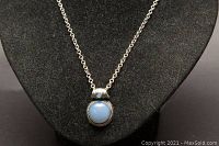 Close-up photo of the blue pendant on the silver chain, showing pendant details.