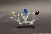 Front view of three Swarovski crystal tulip figurines in yellow, blue, and red mounted on a curved stand