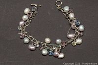 Full view of the bracelet showing freshwater pearls, crystals, and toggle clasp on black background.