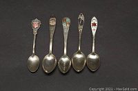 Photo showing the five sterling silver collector spoons arranged side-by-side with visible decorative handles and spoon bowls.