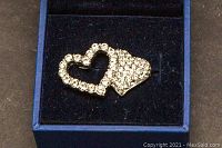 Close-up of Swarovski heart-shaped crystal brooch on black velvet surface inside box