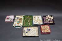 Overview of multiple jewelry boxes containing assorted vintage costume jewelry including necklaces, brooches, and earrings.