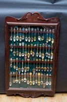Full view of wooden Bombay Co display case containing approximately 60 collector spoons mounted inside