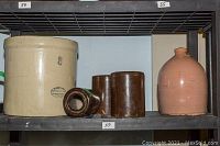 Shelf display of large Medalta crock, brown stoneware jars, and pink jug to show overall lot contents