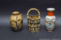 Full view of all three Asian decorative items: tan vase, basket-shaped teapot, and white porcelain vase with birds.