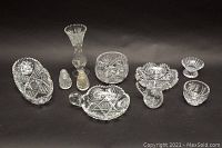 Full set of nine pinwheel cut crystal items on black background showing bowls, bud vase, creamer, sugar bowl, and shakers.
