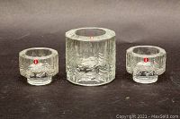 Front view of three glass votive candle holders with fir tree pattern and Iittala stickers.
