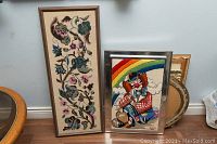 Needlepoint wall decorations displayed together showing relative size and framing styles.