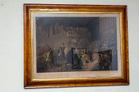 Full view of the framed engraving on the wall showing the artwork and wooden frame.