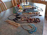 Overview of jewelry collection including necklaces, bracelets in various colors and materials arranged on the table.