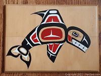 Flat wood panel with painted orca design showing formline style in black, red, white on natural wood background.