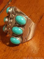 Close-up photo of the silver ring front showing three turquoise cabochons in a vertical row with cutout silver ladder design.