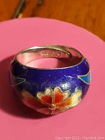 Close-up view showcasing the blue enamel with intricate floral motifs and 925 sterling silver stamp inside the band.