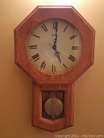 Front view of German-made Kieninger Regulator wall clock with octagonal oak case and Roman numeral clock face.