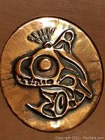 Close-up photo of the oval copper repousse medallion showing detailed stylized animal face design.