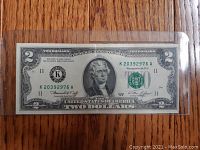 Front of 1976 US two dollar bill in clear protective sleeve, showing serial number K20392976A and Thomas Jefferson portrait.